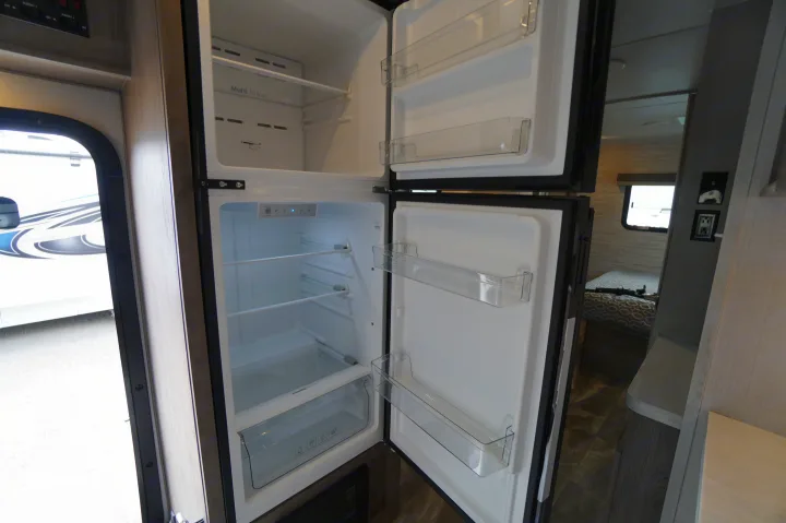 Inside an RV rental: a clean, open two-door refrigerator and freezer, ready for your travel essentials.. Gulf Stream Conquest 2024