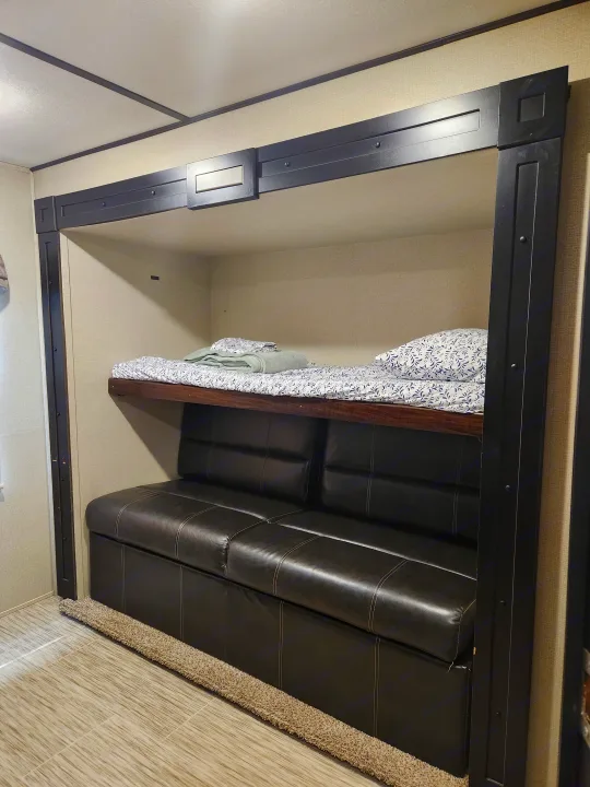 Cozy RV rental interior features comfortable bunk beds over a black leather sofa, perfect for compact family living.. Prime Time Lacrosse 2019