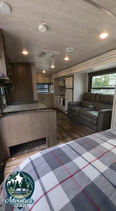 Spacious RV rental interior: kitchen, dining, living room with recliners, and cozy bedroom area. Ready for adventure!. Keystone RV Cougar 2021