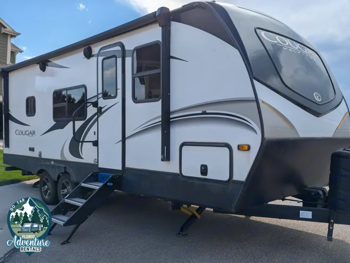 White Cougar travel trailer, an excellent rv rental with a large front window, awning, steps, and stabilization jacks.. Keystone RV Cougar 2021