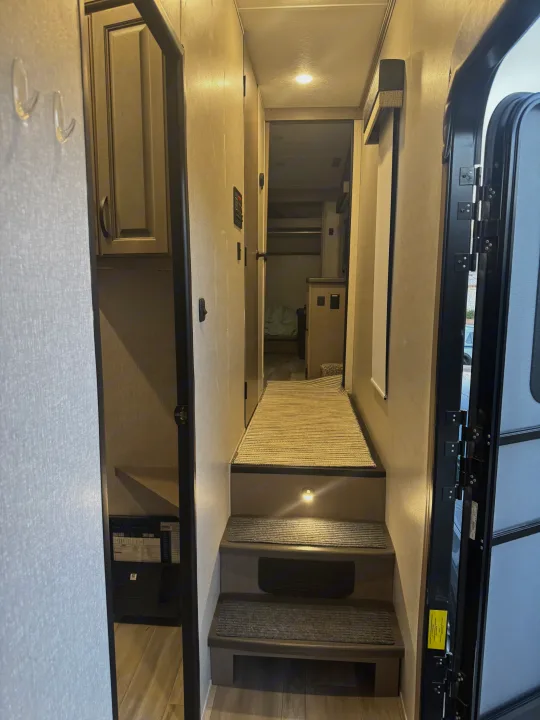 RV rental interior: A multi-level hallway with steps, lights, and a main entry door, offering a glimpse into the living space.. Coachmen Chaparral 2022
