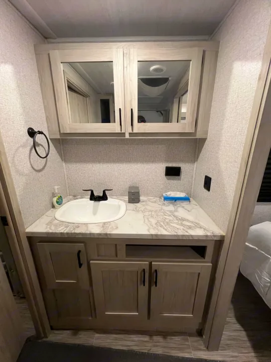 Compact and clean RV rental bathroom vanity with sink and mirrored cabinet, perfect for your travels.. East to West Silver Lake 2022
