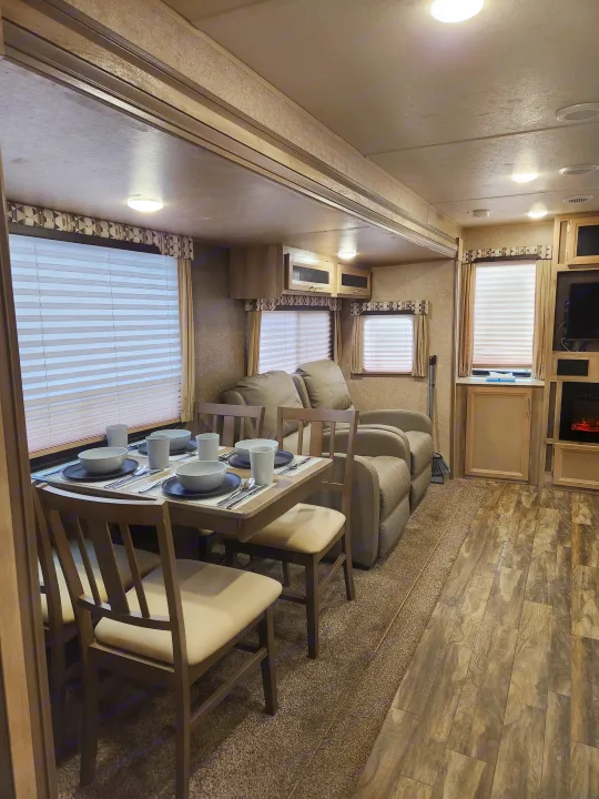 Explore this modern RV rental's interior featuring a cozy dining area, plush reclining sofa, and ample living space.. Coachmen Catalina 2020