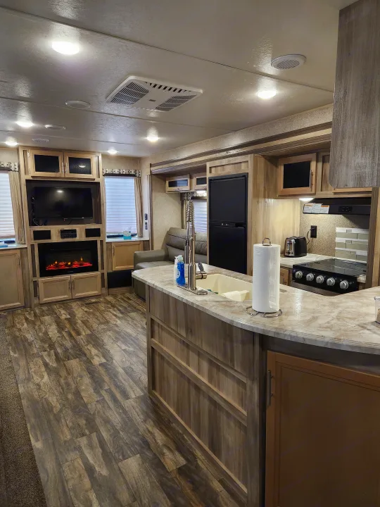 Clean RV rental interior showing a full kitchen, entertainment center with TV & fireplace, and comfortable living space.. Coachmen Catalina 2020