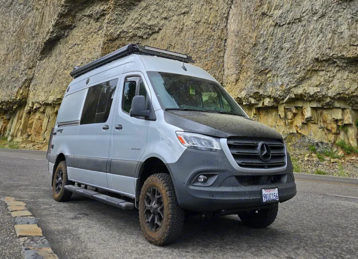 Adventure awaits with this custom Mercedes Sprinter van, ideal for rv rental trips. Parked roadside by a textured rock face.. Entegra Coach Launch 2023