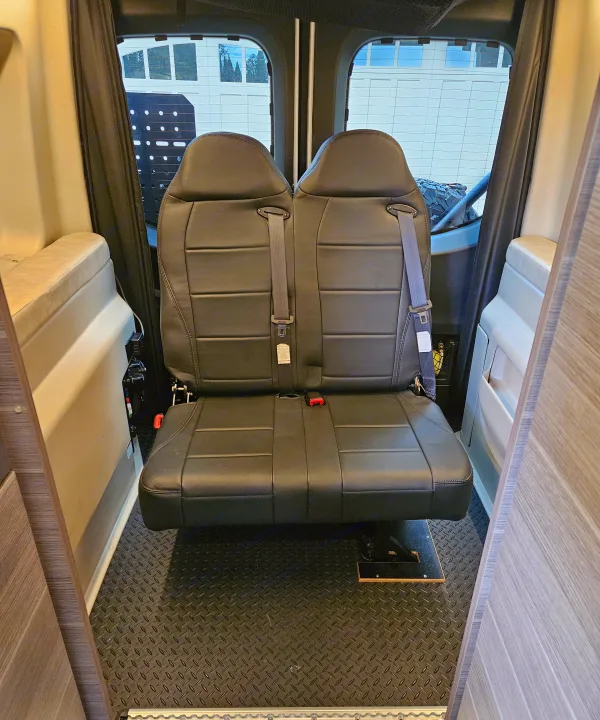 RV rental: View of two black passenger seats with seatbelts and textured diamond-plate floor for passenger safety.. Entegra Coach Launch 2023