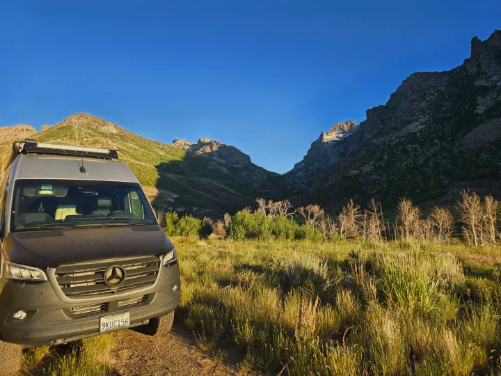 Mercedes-Benz Sprinter RV rental amidst sunlit mountains & grass. Enjoy scenic off-grid adventures & van life exploring nature.. Entegra Coach Launch 2023