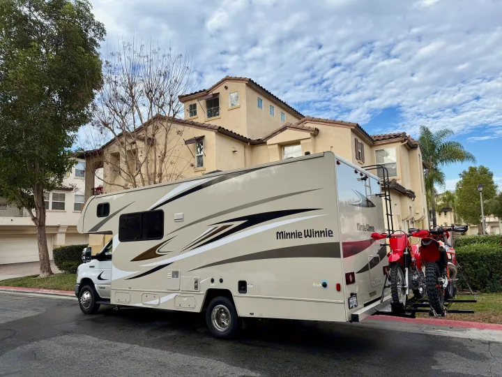 This RV rental, a Minnie Winnie, is parked with two red dirt bikes on its rear rack, perfect for an off-road adventure.. Winnebago Minnie Winnie 2020
