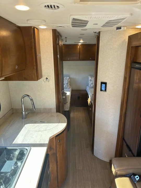 Spacious RV rental interior featuring a compact kitchen, hallway leading to twin beds, and modern amenities for comfortable travel.. Wayfarer Wayfarer Motorhome 2018