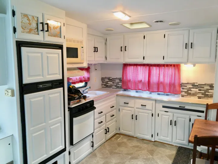 Bright, renovated RV rental kitchen with white cabinets, stove, fridge, and microwave.. Jayco Eagle 1998