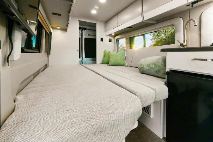 Spacious rv rental interior: comfy bed, mini-kitchen, and scenic window views through a large window.. Entegra Coach Ethos 2024