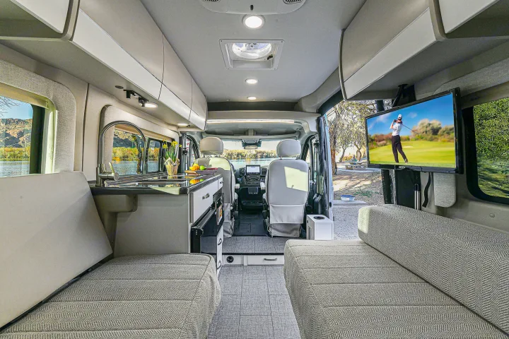 Spacious rv rental interior with kitchen, comfy seating, and TV. Perfect for road trips and relaxation.. Entegra Coach Ethos 2024
