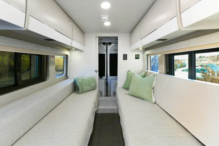 Spacious rv rental interior featuring facing sofas, overhead storage, and large windows for scenic views and comfortable travel.. Entegra Coach Ethos 2024