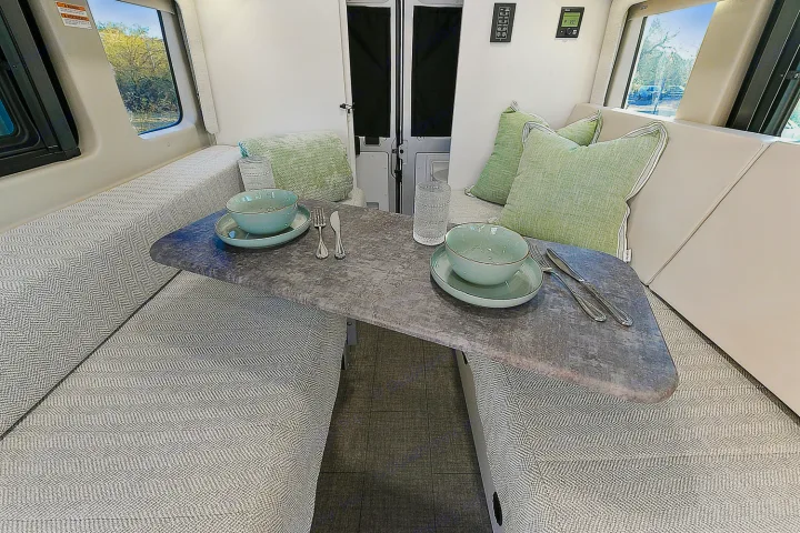 This RV rental offers a comfortable dinette setup with chevron patterned cushions and a stone-look table, ready for dining.. Entegra Coach Ethos 2024