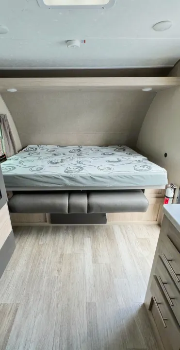 RV rental: Bright interior featuring a bed over a dinette, with a smoke detector & fire extinguisher visible.. Coachmen Catalina 2023