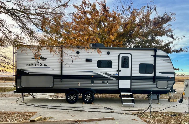 Spacious Jayco travel trailer rv rental parked at an RV park, featuring a modern exterior and autumn trees.. Jayco Jay Flight 2024