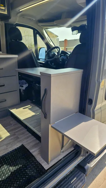 RV rental camper van interior: A versatile front area with a fold-out table, cabinet storage, and driver's seat.. Thor Motor Coach Dazzle 2025