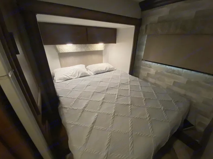 Cozy RV rental bedroom featuring a comfy bed, overhead storage, and ambient lighting, ideal for your travels.. Forest River Forester 2020