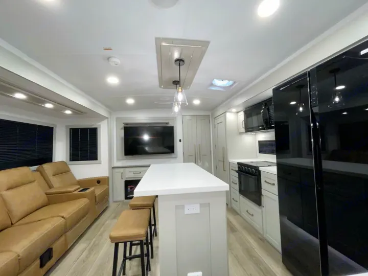 Modern RV rental interior with spacious kitchen, island, and living area with recliners, ideal for comfortable travel.. Brinkley 295 AIR 2025