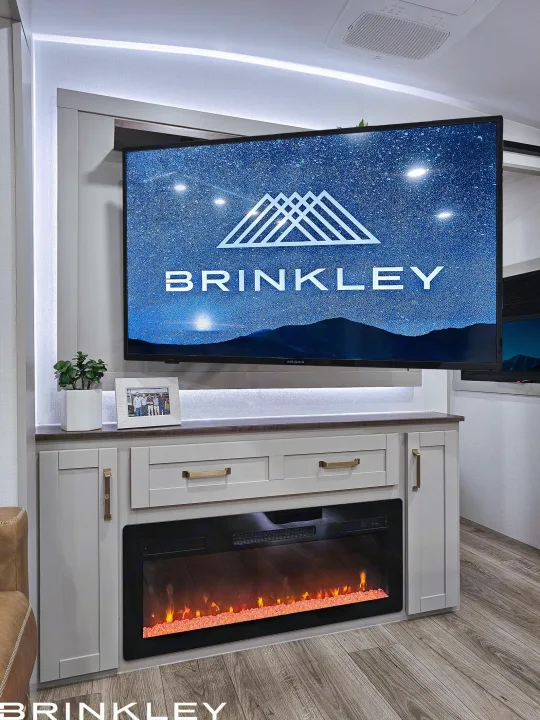 Experience comfort in this modern RV rental: a cozy living area with a large TV, electric fireplace, and ambient lighting.. Brinkley 295 AIR 2025