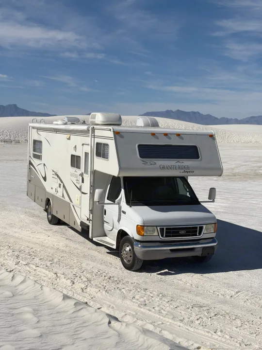 This bright white RV rental stands out against the vast, pale dunes of White Sands National Park, offering unique desert travel.. Jayco Granite Ridge 2003
