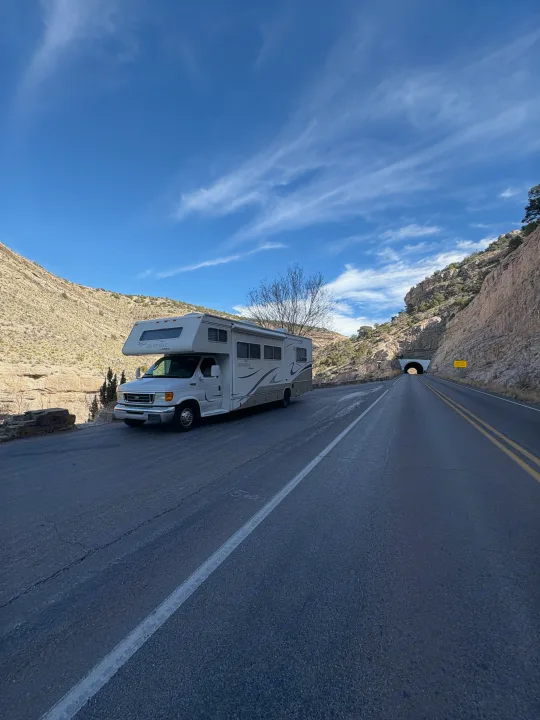 A white RV rental parked on a scenic mountain road, with a tunnel visible in the distance, ready for a road trip.. Jayco Granite Ridge 2003