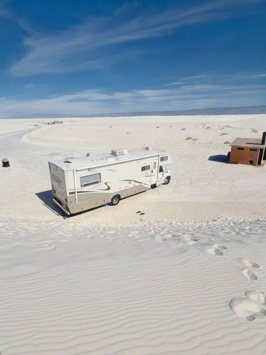An RV rental is parked on the stunning white gypsum dunes of White Sands National Park under a bright blue sky.. Jayco Granite Ridge 2003