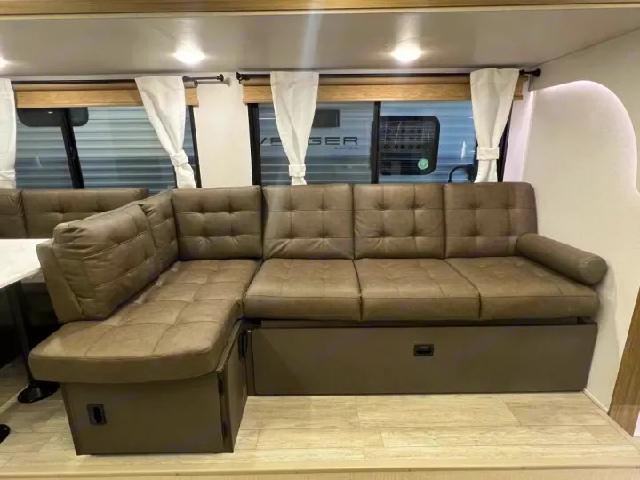 Cozy RV rental interior: A large, comfortable L-shaped sofa with tufted cushions, perfect for mobile living.. Forest River Wildwood X-Lite 2025