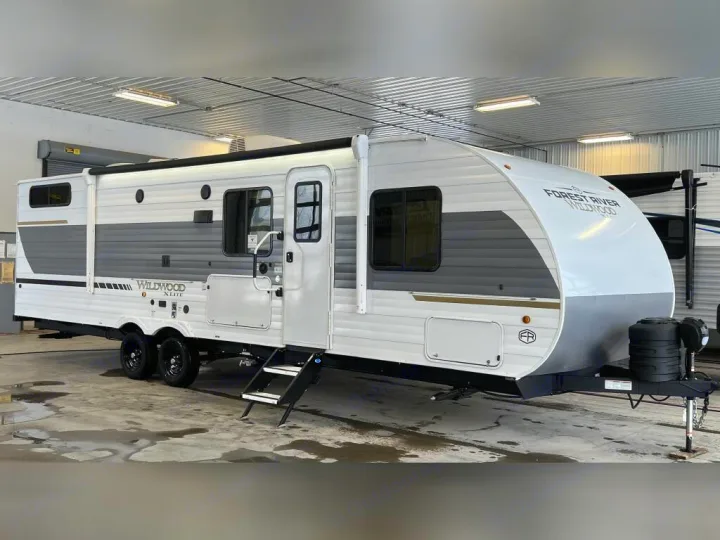 Discover this spacious white and grey travel trailer for your next RV rental. Features steps and dual axles for stable travel.. Forest River Wildwood X-Lite 2025