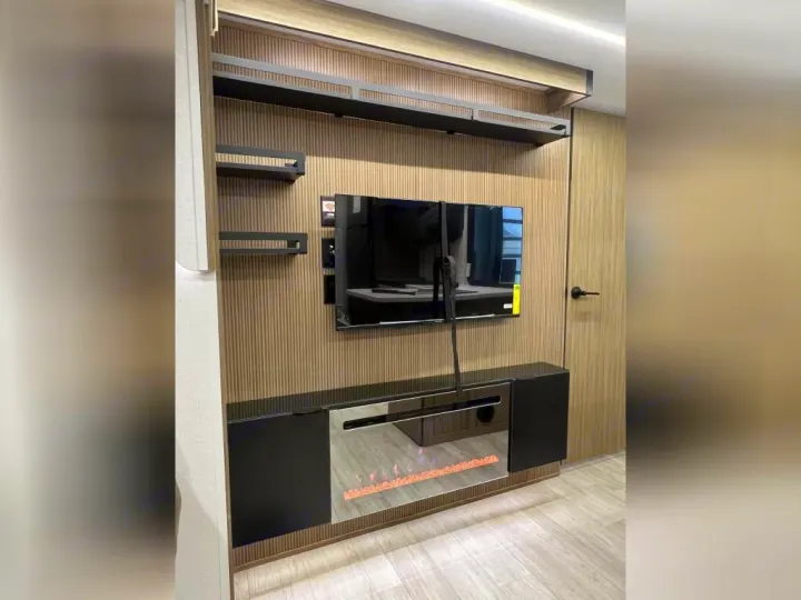 Modern RV rental: Integrated entertainment unit with a TV, electric fireplace, and shelves set against a slatted wall.. Forest River Wildwood X-Lite 2025