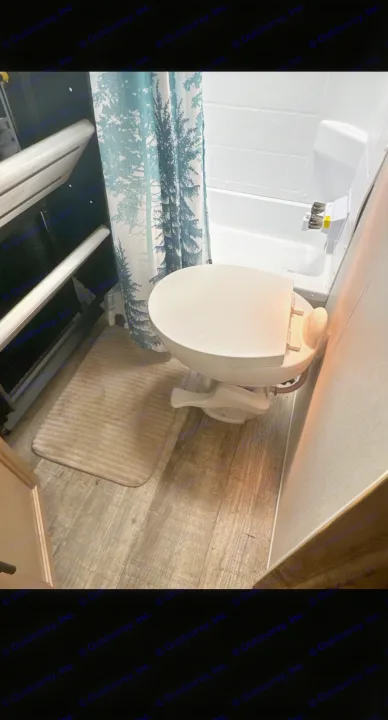 Compact RV rental bathroom showing toilet, shower, and patterned curtain, designed for efficient use of space.. Forest River Cherokee Alpha Wolf 2023