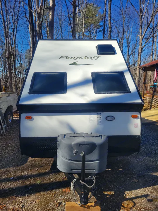 Front view of a white Flagstaff travel trailer. Features include front windows, hitch, and propane tank cover, ideal for RV rental.. Flagstaff A Frame 2015