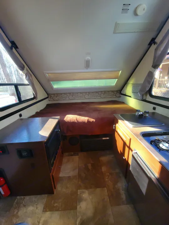 Inside a compact RV rental: features a comfortable bed, kitchen with sink/stove, and microwave. Ideal for travel adventures.. Flagstaff A Frame 2015