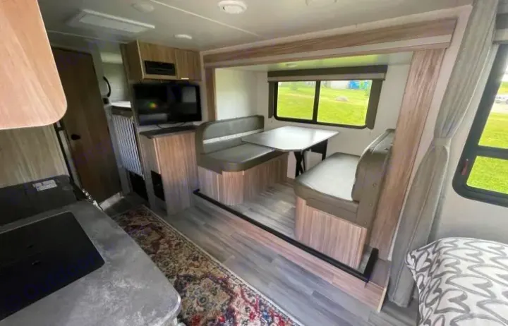 View inside a modern RV rental: cozy dinette with table, compact kitchen, and TV. Perfect for road trips.. Winnebago Micro Mini 2306BHS 2019