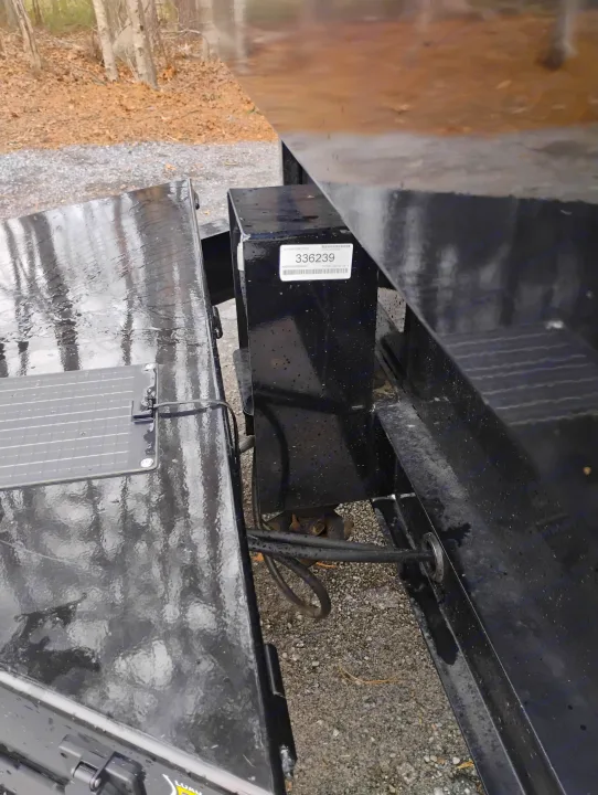 RV rental: Detailed view of a wet, black structural component with serial #336239, exposed wiring, and a solar panel.. Load Trail Dump Trailer 2025