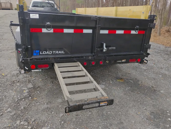 Black dump trailer with an extended ramp. Ideal for debris removal & heavy hauling, complementing RV rental trips.. Load Trail Dump Trailer 2025