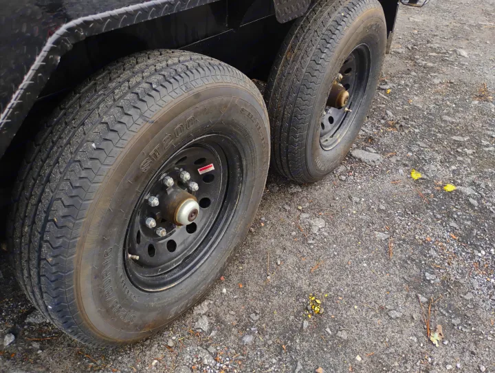 Close-up of dual tires on an RV rental trailer, showcasing tread, wheels, and a diamond plate fender.. Load Trail Dump Trailer 2025