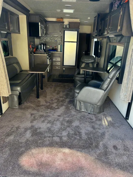 Spacious rv rental interior with comfortable grey seating, tables, full kitchen, and carpeted living area for travel.. Forest River Sandstorm 2017