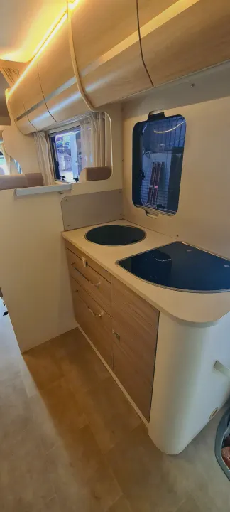 Explore this compact RV rental kitchen featuring a modern sink, stovetop, and ample storage, ready for your next adventure.. Ford Transit Rimor Evo Sound 7 2022
