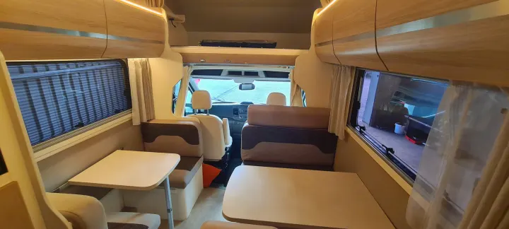 Spacious, modern RV rental interior with dual dining areas and a view into the front cabin.. Ford Transit Rimor Evo Sound 7 2022