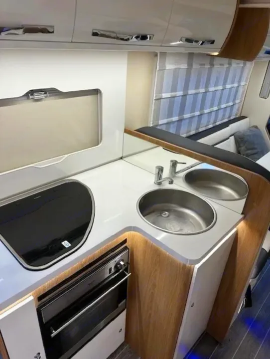 Explore this modern RV rental kitchen with a sleek hob, double sink, and oven, perfect for travel cooking.. Fiat Ducato Rollerteam Autoroller 707 2021