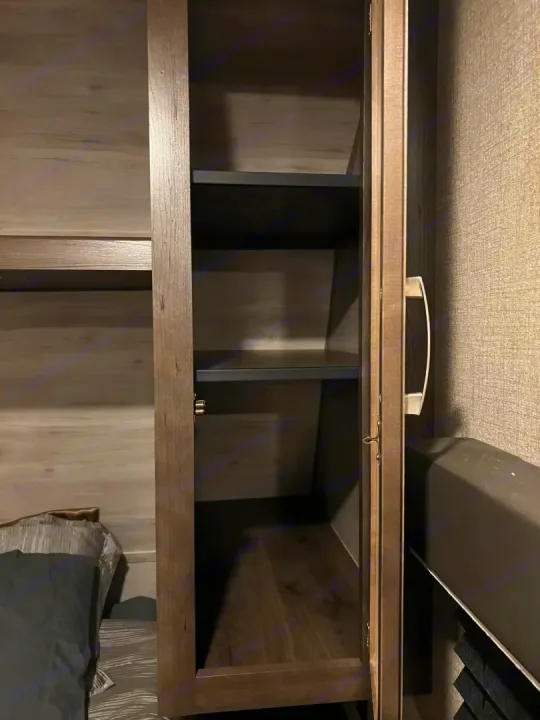 Open, narrow wood-grain cabinet with shelves inside an RV rental bedroom, perfect for compact storage.. Jayco Jay Flight SLX 2021
