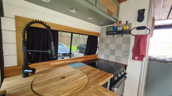 Well-equipped RV rental kitchen: wood counters, sink, black stove, patterned backsplash & storage. Ideal for your camper van trip!. Citroen Relay L3H2 2022