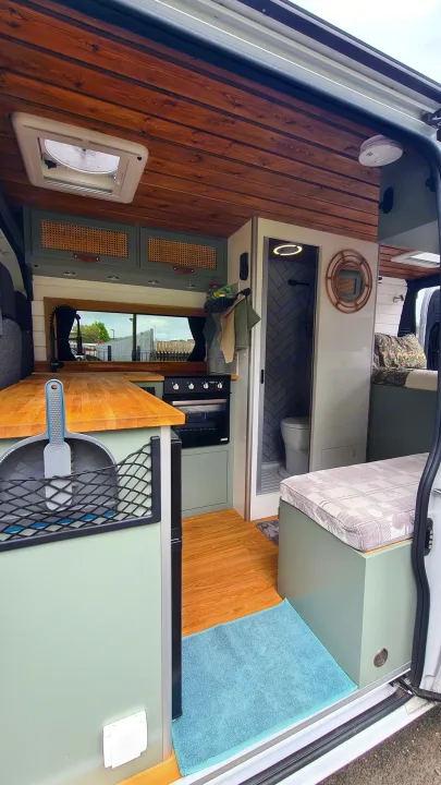 View of a modern **rv rental** interior: wooden ceiling, olive green cabinets, full kitchen, and a compact bathroom.. Citroen Relay L3H2 2022