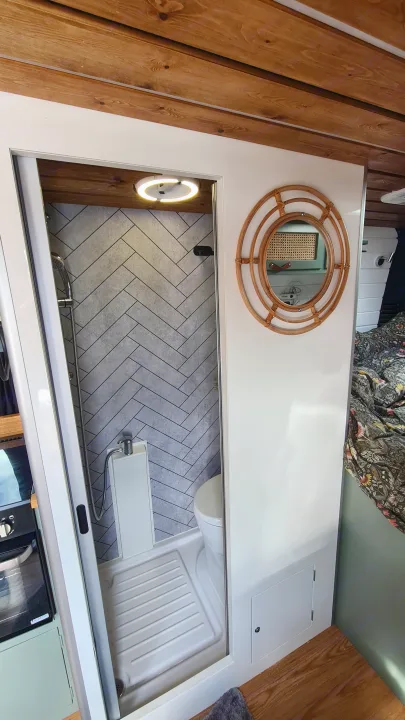 This RV rental's clever design features a compact bathroom with herringbone tile shower, toilet, and round mirror.. Citroen Relay L3H2 2022