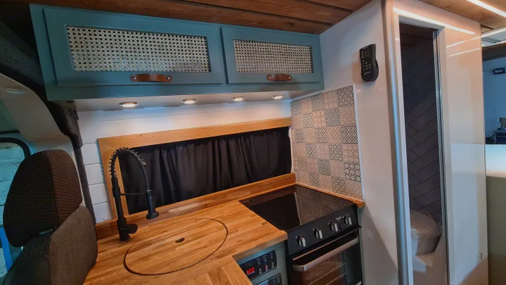 Modern RV rental kitchen with bespoke wooden countertop, black sink, stove, tiled backsplash, and stylish rattan cabinets.. Citroen Relay L3H2 2022
