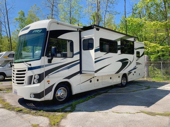 This white & black Forest River FR3 motorhome with a slide-out is ready for an rv rental, parked outdoors under a blue sky.. Forest River Fr3 2021