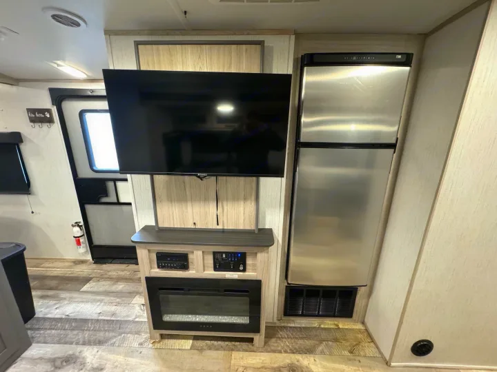 Cozy RV rental living space featuring a large TV, electric fireplace, and full-size refrigerator. Ready for your adventure.. Heartland Sundance 2023