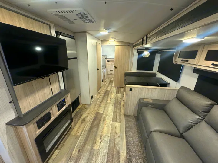 Explore this RV rental's inviting interior: TV, fireplace, sofa, dinette, fridge, and bunks.. Heartland Sundance 2023