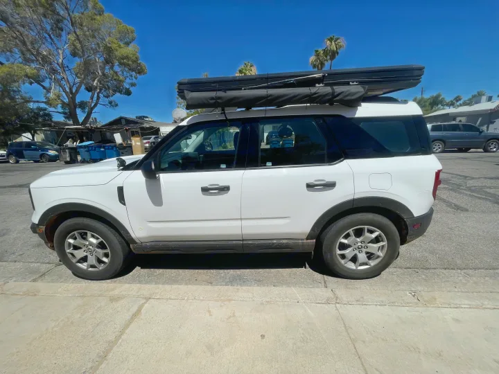 White Ford Bronco Sport SUV with black rooftop tent for adventurers. Consider this versatile option instead of an RV rental.. Ford Bronco sport 2022